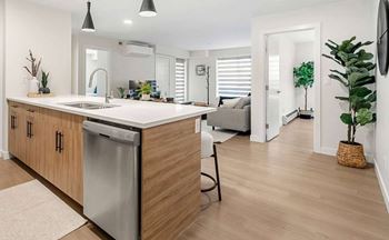 A modern kitchen with wooden cabinets and a dishwasher.at Skyway Apartments, Calgary, AB